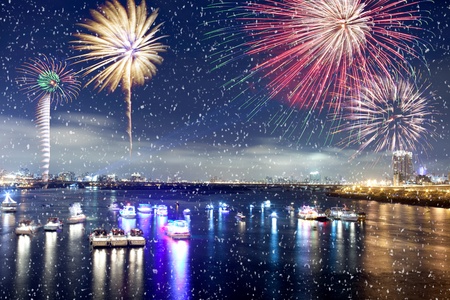 Fireworks firing up into the sky with a boat on a river below them, with a reflection on the water の写真素材