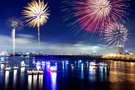 Fireworks firing up into the sky with a boat on a river below them, with a reflection on the water の写真素材