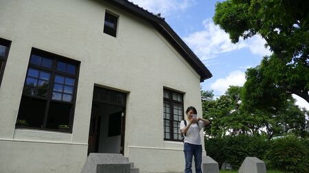 The young girl stand beside the house watching the smart phoneのeditorial素材