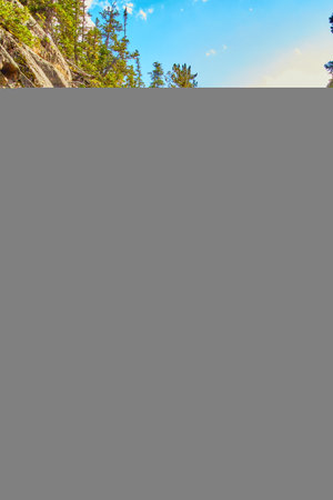 Vertical of waterfall through large boulders in mountains with lichen rocksの写真素材