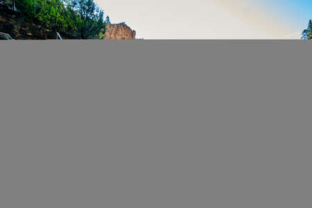 Stone steps in mountains with metal railing leading up mountain with view of large cliffs and forestの写真素材