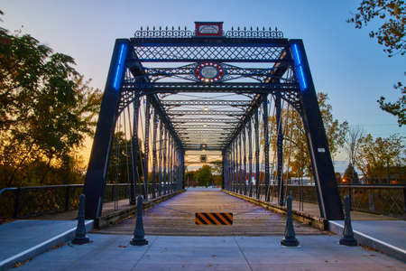 Old fashioned metal walking bridge at sunset with blue lightsの写真素材