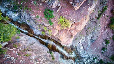 Tall waterfall in gorge falling of cliff edge from very top viewの写真素材