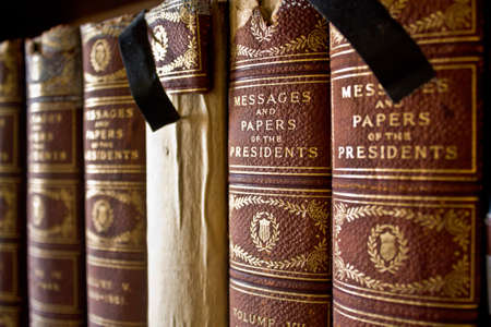 Old books bound with cloth lined up on a shelf