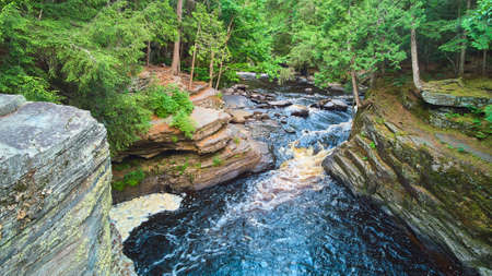 View inside vibrant gorge with waterfalls and lichen covered rocks in forestの写真素材