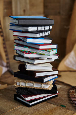 Stack of small multicolored handcrafted books on a wooden surfaceの写真素材