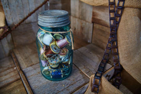 Mason jar full of spools of thread sitting on a wooden surfaceの写真素材