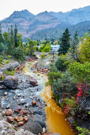 Clear and brown rivers mixing together in gorge with mountains in the backgroundの写真素材