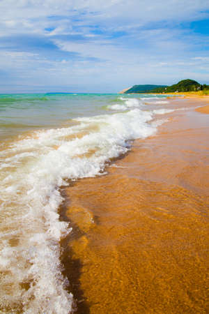 White foaming waves crest upon a sandy beachの写真素材