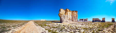 Panorama of dirt road in desert with large vertical rock obelisksの写真素材