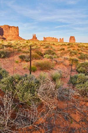 Detail of shrubs and fence in desert with red rock pillars Monument Valleyの写真素材