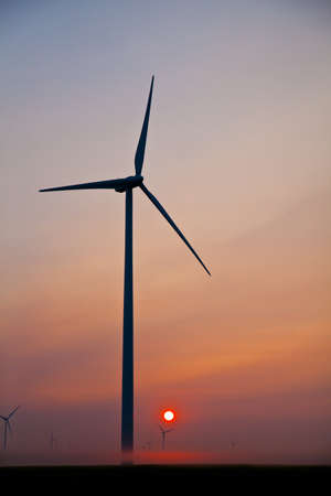 Windmill silhouetted against the oranges of a setting sunの写真素材
