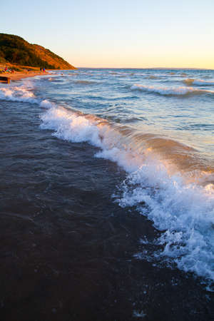 White crested waves roll towards the beach with a mountain and the horizon in the backgroundの写真素材
