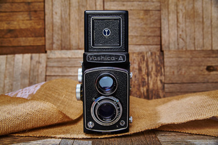 Landscape of a very old style camera on top of burlap fabric in front of a wooden wallの写真素材