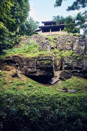 Vertical of structure with stone wall on stone cliffs next to green fieldの写真素材