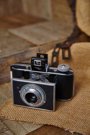 Antique film camera sitting on burlap cloth on a wooden surface