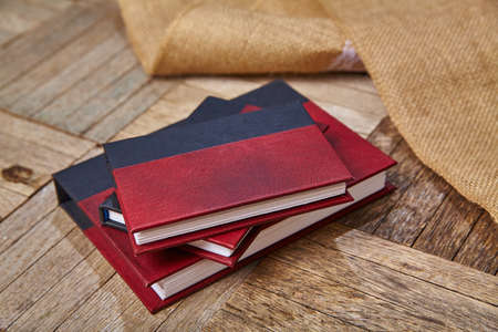 Three small red and black journals laying next to burlap cloth on a wooden surfaceの写真素材