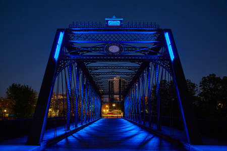Metal bridge leading into downtown glows blue at nightの写真素材