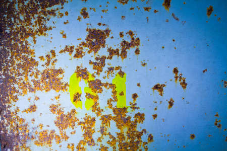 Blue metal wall pocked with rust and numbers spray painted in yellowの写真素材
