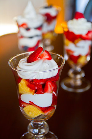 Mixed fruit parfait in a clear transparent glass with colorful layers and topped with strawberriesの写真素材