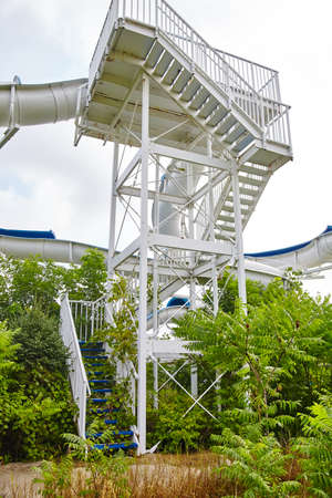 Shot of the base of a staircase overgrown with greenery and shrubs leading up to a water slideの写真素材