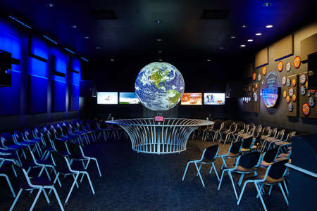 Glow in the dark science room with many chairs facing a suspended globeの写真素材