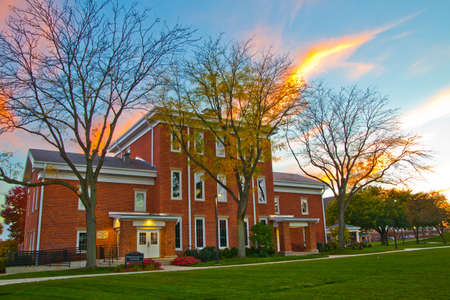 Colonial style red brick building with lush green lawn at sunsetの写真素材