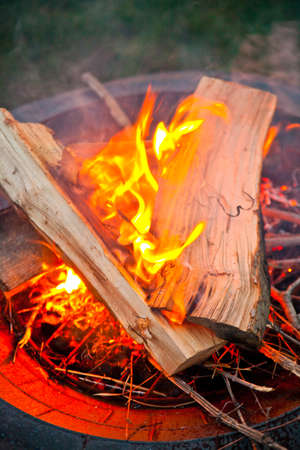 Twilight fire in a pit with logs on top of curling flameの写真素材
