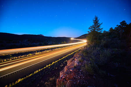 Time lapse long exposure shot of traffic streaking across a road