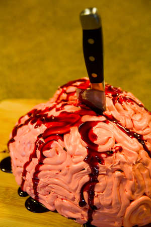 Realistic Halloween brain cake treat stabbed with a knife and flowing with red blood sauceの写真素材