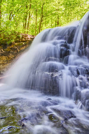 Vertical close-up of white waterfall cascading over rocky cliffの写真素材