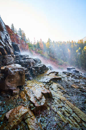 Waterfall splashing down on wet and slippery rocks from behindの写真素材