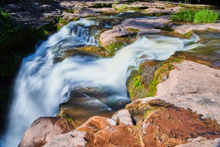 Close up of waterfall edge over mossy brown rocksの写真素材