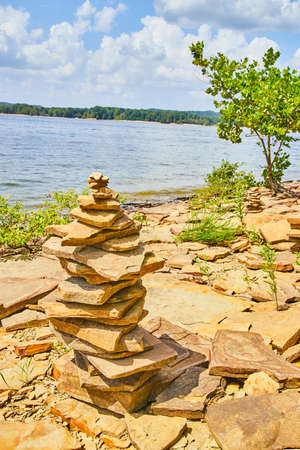 Stack of stones (cairn) on warm beach with rocksの写真素材