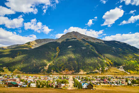 Landscape of mountain range and blue skies behind small mining townの写真素材