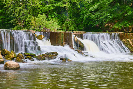 Dam with manmade waterfalls and background of green forestの写真素材