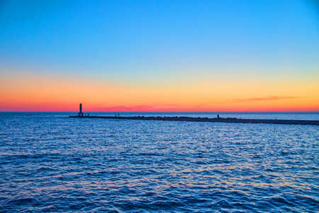 Beautiful sunset or sunrise on lake with pier silhouette and colorful sky of red, orange, and blueの写真素材