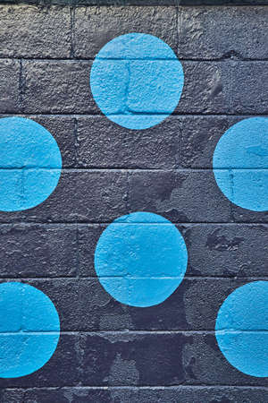 Vertical of black painted cement block wall up close with circles of blueの写真素材