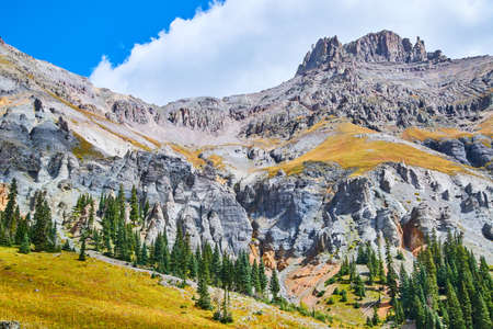 Mountain with columns of gray rock and sharp peaks with pine trees at baseの写真素材