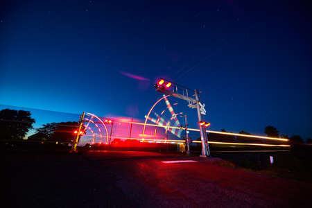 Railroad crossing and a speeding train in motion at duskの写真素材