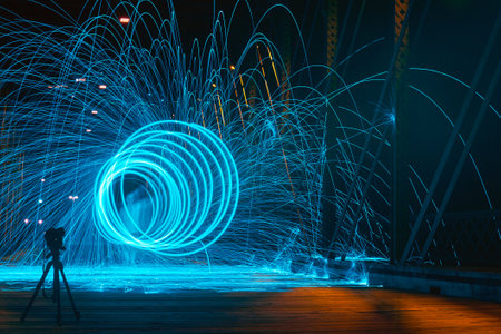 Blue tunnel of blue sparks on a bridge at night with a ghostly visage of a man and a camera nearbyの写真素材