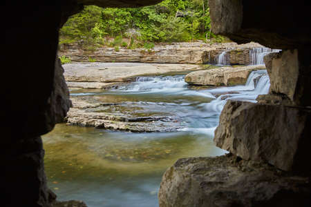 Cave looking out over Cataract Falls with river, rocks, forest, and basinの写真素材