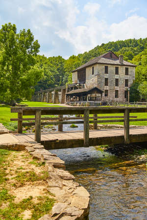 Old Stone Mill with wooden walking bridge over tiny creekの写真素材