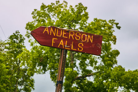 Road sign for Anderson Falls with green trees in background