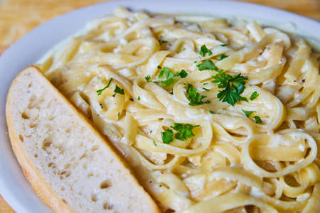 Delicious and fresh traditional italian fettuccini alfredo with bread and parsleyの写真素材