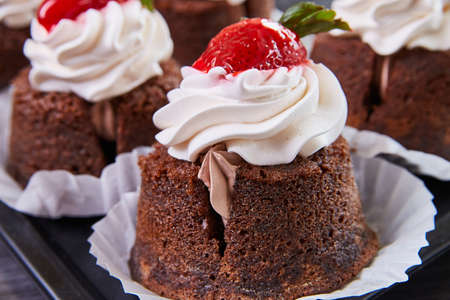 Detail of delicious bakery cupcake filled with frosting and topped with cherry
