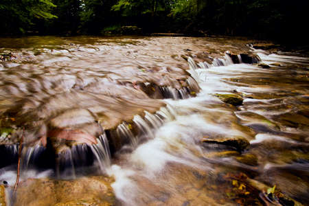 Close view of small waterfalls over rock shelf in river