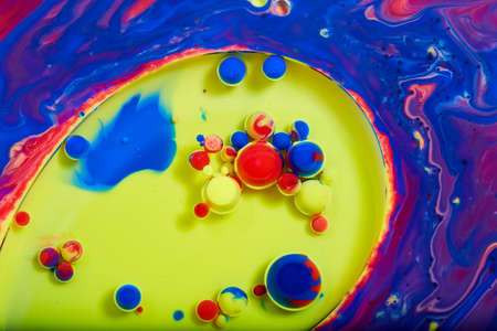 Tiny colorful spheres of red, yellow, and blue on mystical liquid surface