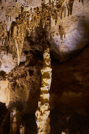 Large stalagmite and stalactites in golden caveの写真素材