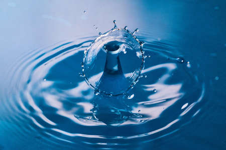 Two water drops colliding on clean blue surfaceの写真素材
